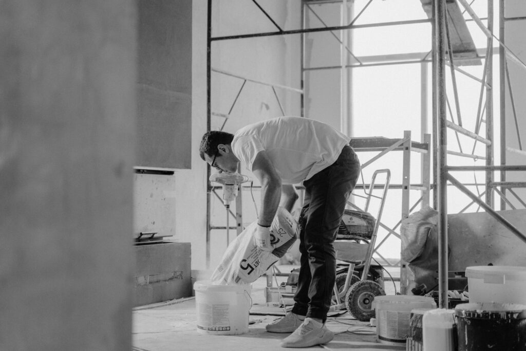 A construction worker pours materials inside a building under renovation.