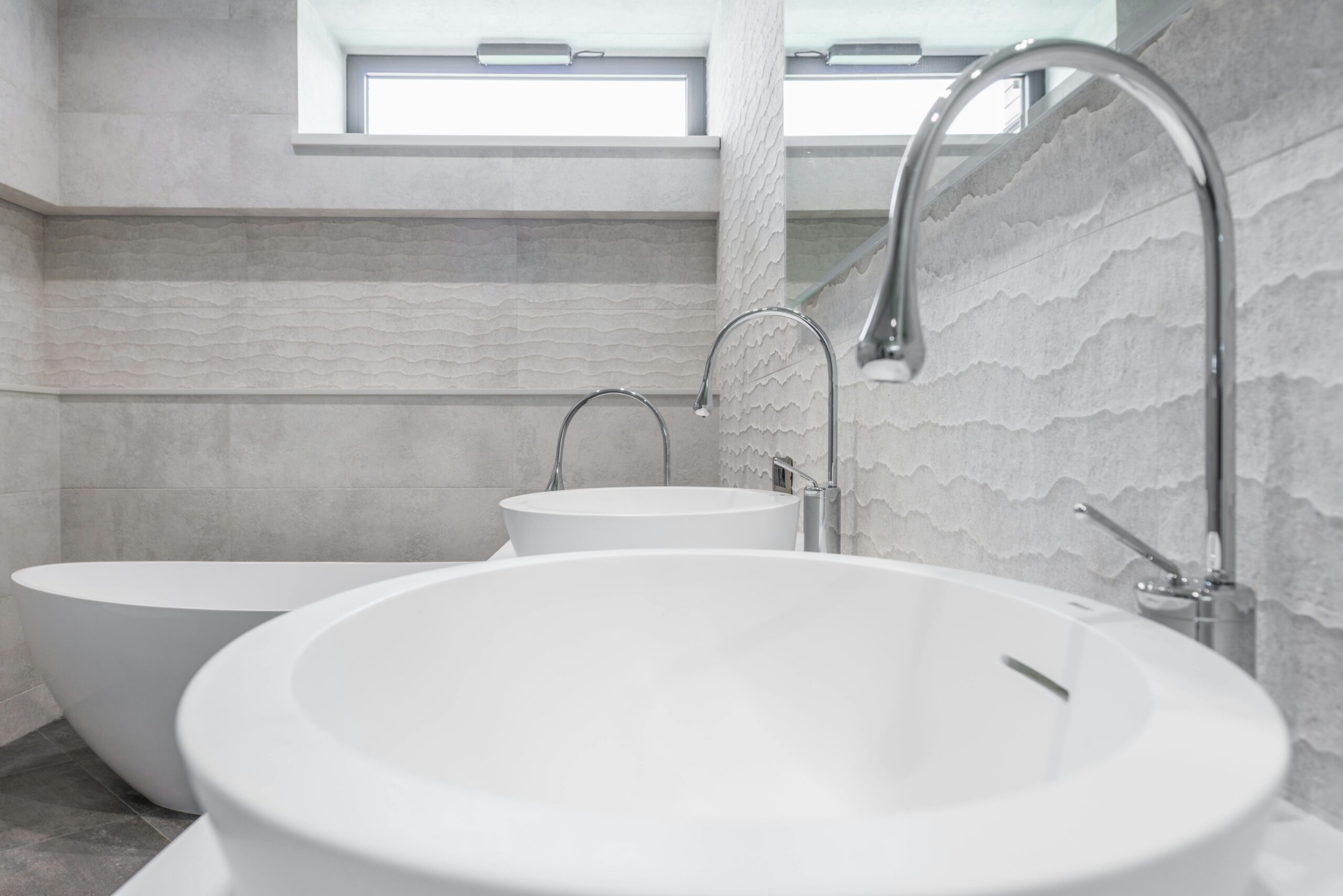 White ceramic sinks and chrome faucets installed in modern bathroom with light gray walls in contemporary luxury house